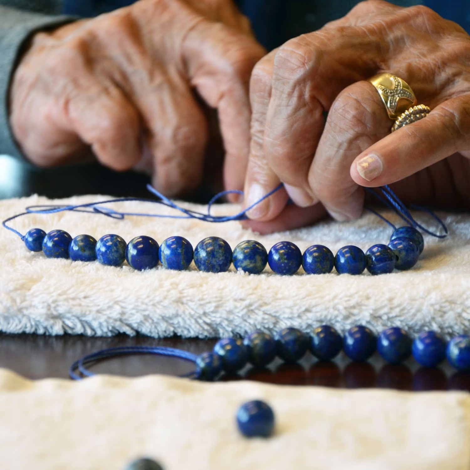 Female Afghan jeweller working with lapis lazuli beads and gold settings.